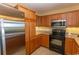 Modern kitchen with stainless steel refrigerator and microwave with black oven and brown cabinetry at 8121 Amalfi Pl. # 4-702, Myrtle Beach, SC 29572