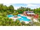 Aerial view of a large community pool and a charming red barn-style clubhouse surrounded by trees at 2385 Windmill Way, Myrtle Beach, SC 29579