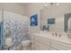 Well-lit bathroom with a single vanity, framed mirror, and a shower with a blue floral curtain at 265 Venice Way # 1-201, Myrtle Beach, SC 29577