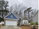 Charming single-story home featuring stone accents, blue siding, a two-car garage, and a well-manicured lawn at 414 Antietam Place, Little River, SC 29566