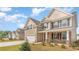 Two-story home with tan siding, dark shutters, stone accents, attached two-car garage, and a well-manicured lawn at 7006 Shooting Star Way, Myrtle Beach, SC 29579