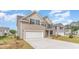 Angle view of a two-story home with a two-car garage, tan siding, stone accents, driveway, and landscaped yard at 7006 Shooting Star Way, Myrtle Beach, SC 29579