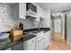 Well-lit kitchen with white appliances and cabinets, granite countertops and modern backsplash at 7509 N Ocean Blvd. # 1203, Myrtle Beach, SC 29572