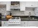 Close-up of kitchen with white cabinets, black granite counters and modern backsplash at 7509 N Ocean Blvd. # 1203, Myrtle Beach, SC 29572