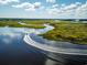 Aerial shot of a boat cruising on the river through beautiful green marshland at 1145 Windy Grove Ln Sw # 16, Ocean Isle Beach, NC 28469