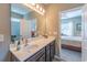 Bathroom with a dark wood vanity, sink, and large mirror reflecting the adjacent bedroom through an open doorway at 1182 Palm Crossing Dr., Little River, SC 29566