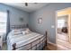 Cozy bedroom with a metal bed frame, soft blue walls, and light-filled doorway at 1182 Palm Crossing Dr., Little River, SC 29566