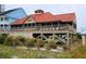 Beachfront building on stilts with a red roof, surrounded by lush dune vegetation at 1221 Tidewater Dr. # 2821, North Myrtle Beach, SC 29582