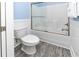 Modern bathroom with sleek sliding glass door shower, white fixtures, and stylish gray wood-look flooring at 1411-A N Ocean Blvd., Surfside Beach, SC 29575