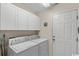 Functional laundry room with white cabinets, appliances, and access door at 199 Glenwood Dr., Conway, SC 29526