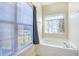 Bright bathroom featuring a soaking tub, large window with blinds, and decorative window treatment at 221 Hagley Dr., Pawleys Island, SC 29585