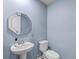 Stylish half-bathroom features a modern octagonal mirror, pedestal sink, and a standard toilet, enhanced by soft blue walls at 224 Pine Forest Dr., Conway, SC 29526