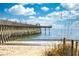 View of the pier and the ocean from the beach on a sunny day with blue skies at 400 20Th Ave. N # 101, Myrtle Beach, SC 29577