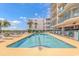 Outdoor pool with lounge chairs, palm trees, and residential building at 4301 S Ocean Blvd. # 7A, North Myrtle Beach, SC 29582