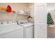 Bright laundry room featuring a washer, dryer, storage shelf and a glimpse of a decorated Christmas tree at 4882 Luster Leaf Circle # 305, Myrtle Beach, SC 29577