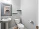Cozy half-bathroom featuring a pedestal sink, toilet, decorative mirror, and minimalist design at 5230 Piemonte Ln., Myrtle Beach, SC 29579