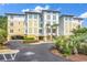 Low angle, three story building featuring yellow and white siding and a tropical landscape at 1352 Villa Marbella Ct. # 1-304, Myrtle Beach, SC 29572