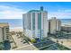 A high-rise condominium building boasts an oceanfront location with beach views and palm trees at 2301 S Ocean Blvd. # 1401, North Myrtle Beach, SC 29582