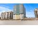 Exterior day view of condo building on the beach with palm trees in front and an elevated walkway to the beach at 2301 S Ocean Blvd. # 1401, North Myrtle Beach, SC 29582