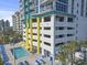 Exterior view of a pool with yellow sunshades next to a condo building, surrounded by blue lounge chairs and palm trees at 2301 S Ocean Blvd. # 1401, North Myrtle Beach, SC 29582