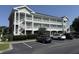 Exterior view of a three-story condominium building with white balconies and well-maintained landscaping at 3955 Gladiola Ct. # 301, Myrtle Beach, SC 29588