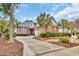 Beautiful red brick home featuring a well-manicured front yard with palm trees and circular driveway at 602 Sea Vista Ln., North Myrtle Beach, SC 29582