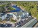 Aerial view of a white condo building with a pool, parking lot, and golf course near a tranquil lake at 131 Greenside Villas Dr. # B10, Little River, SC 29566