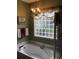 Well-lit bathroom featuring a soaking tub, elegant chandelier, and decorative window at 1822 Topsail Ln., North Myrtle Beach, SC 29582