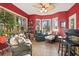 Cozy sunroom with red walls, tile floor, ceiling fan, an array of windows, and comfortable seating to enjoy nature views at 1822 Topsail Ln., North Myrtle Beach, SC 29582