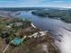 Wide aerial shot showcasing blue tennis courts near a tranquil body of water and winding river at 2120 Adams Way, Little River, SC 29566