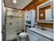 Bathroom with wood paneling features glass enclosed shower, white vanity, and matching cabinet at 2120 Adams Way, Little River, SC 29566