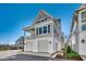 Angle view of a gray home with a two-car garage, balcony, manicured lawn, and stylish architecture at 223 Gloucester Way, Little River, SC 29566