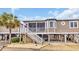 Charming coastal home on stilts with a screened porch, white stairs, and tropical landscaping at 299 Lake Arrowhead Rd., Myrtle Beach, SC 29572