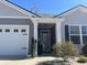 Close up of the front door with black shutters, a garage door, and well maintained landscaping at 3009 Woodbury Ct., Conway, SC 29527