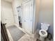 Bathroom with a toilet, two white doors, grey flooring, grey walls, and a closet entrance at 311 Las Olas Dr., Myrtle Beach, SC 29577