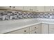 Close-up of a kitchen with gray cabinets, mosaic backsplash, and white countertops at 445 Mooreland Dr., Myrtle Beach, SC 29588