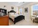 Cozy bedroom with a black bed frame, floral accents, and a reading chair next to window with blinds at 446 Deerfield Links Dr., Surfside Beach, SC 29575