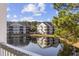 Exterior view of condos reflecting in a serene pond, surrounded by lush trees under a blue, cloudy sky at 5060 Windsor Green Way # 304, Myrtle Beach, SC 29579