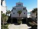 Beach house on stilts with a view of the ocean and palm trees, featuring a ground-level covered parking area at 547 South Waccamaw Dr., Garden City Beach, SC 29576