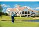 Golfer swinging on a pristine green with a beautiful clubhouse and scenic water hazard at 8155 Living Tide Dr., Myrtle Beach, SC 29572