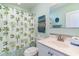 A full bathroom with a palm tree patterned shower curtain, white vanity, and coastal decor at 124 B Vista Dr., Murrells Inlet, SC 29576