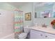 Well-lit bathroom with marble counter, decorative mirror, patterned shower curtain, and modern toilet at 124 B Vista Dr., Murrells Inlet, SC 29576