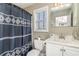 Compact bathroom featuring a shower with patterned blue curtain, window and classic white vanity at 124 B Vista Dr., Murrells Inlet, SC 29576