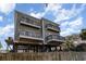 Charming elevated beach home with four balconies, sturdy pilings, and string lights for outdoor enjoyment at 124 B Vista Dr., Murrells Inlet, SC 29576