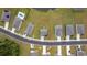 An aerial view shows multiple homes with gray roofs and paved driveways on grassy lots around a pond at 128 Caveson Way, Conway, SC 29526