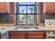 Close-up of kitchen sink with black tile backsplash, granite counters, and backyard view at 1586 Bridgebrook Ln., Conway, SC 29527