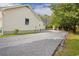 Side view of the house featuring a gravel driveway and a glimpse of the backyard with mature trees at 2264 Wedgefield Rd., Georgetown, SC 29440