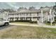 Inviting two-story condo featuring white railings, red shutters, and manicured shrubbery at 3677 Claypond Village Ln. # 4, Myrtle Beach, SC 29572