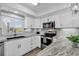 Bright kitchen features white cabinetry, stainless steel appliances, and gorgeous stone countertops at 423 Parker Dr. # 306, Pawleys Island, SC 29585