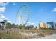 Ferris Wheel near the beach with blue skies, surrounding buildings, and lush greenery at 4305 Frontier Dr., Myrtle Beach, SC 29577